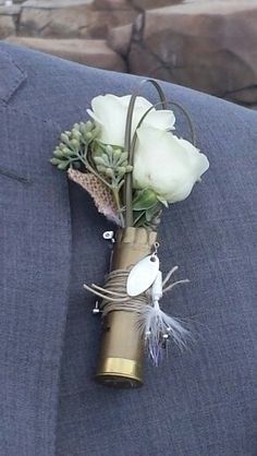 a boutonniere with white flowers and feathers attached to the lapel of a suit