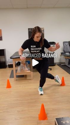 a woman in black shirt and white sneakers doing an exercise with orange cones on the floor