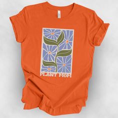 an orange t - shirt that says plant mom on the front and blue flowers in the back