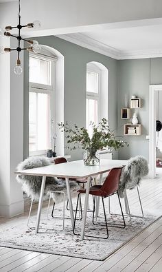 a dining room table with chairs and a rug in front of the table is surrounded by windows