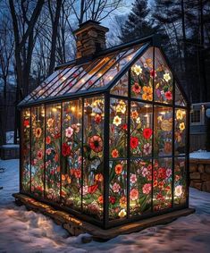 a glass house with flowers painted on it's side and lights in the windows