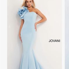 a woman in a light blue gown standing next to a white wall with the word jovani written on it