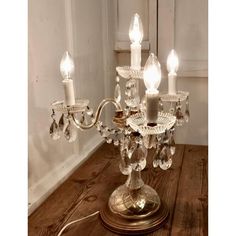 a small crystal chandelier on a wooden table with two candles in the center