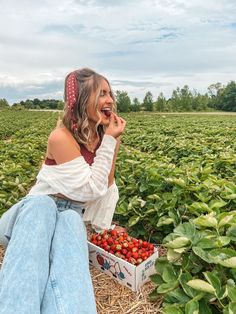 a woman sitting in the middle of a strawberry field