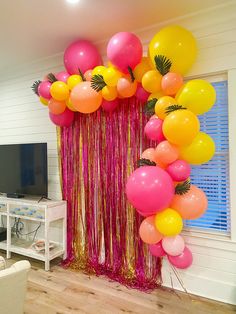 a living room with balloons and streamers on the wall in front of a flat screen tv