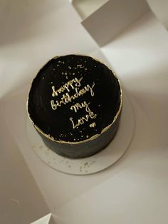 a black and gold birthday cake with writing on it