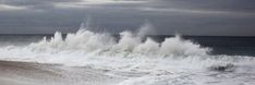 a man riding a surfboard on top of a wave covered beach next to the ocean