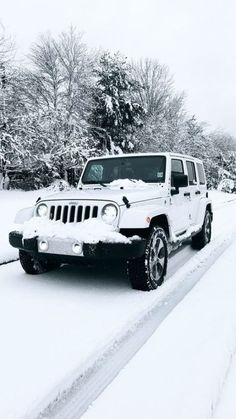 a white jeep driving down a snow covered road