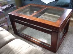 a coffee table with two glass doors on the top and bottom, in front of a couch