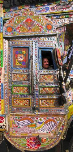 a colorfully painted truck with a man in the window looking out from behind it