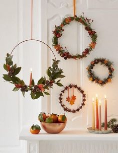 wreaths, candles and fruit are hanging on the mantle in front of a white door