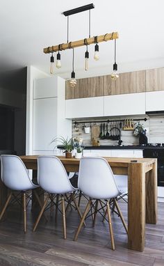 a dining room table with four chairs and a kitchen in the backround behind it