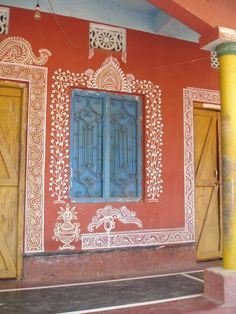 an orange building with blue doors and ornate designs on the wall, in front of a yellow column