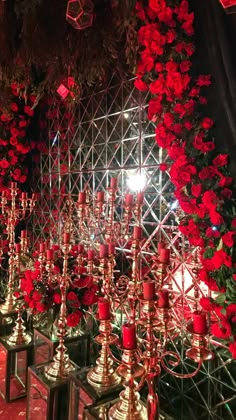 many candles are lit and surrounded by red flowers