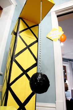 a yellow and black tie hanging from the side of a wall with a ball on it