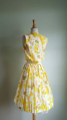 Now that's a cocktail dress! 🍸🍋 This vintage dress looks like an olive martini with a citrus twist, with its fun abstract dot and stem print, bursting with pops of orange, yellow and green on a cream background. It features a blouson-style bodice that buttons in the back; a cinched waist accented by a matching tie sash; and a full, twirly pleated skirt. (Pictured with a crinoline- not included - to demonstrate fullness; its white edge peeks out at the hem.) Bodice is lined; back metal zip at w Spring Sleeveless Dress With Box Pleat, 1950s Style Spring Cocktail Dresses, 1950s Style Sleeveless Cocktail Dress, 1950s Style Summer Cocktail Dress, Sleeveless Summer Cocktail Vintage Dress, Sleeveless Vintage Cocktail Dress, Vintage Sleeveless Party Dress, Retro Sleeveless Spring Party Dress, Yellow Pleated Dress For Cocktail