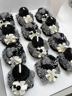 cupcakes decorated with black and white frosting are on a table in a box