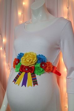 a pregnant woman's belly is adorned with colorful flowers and ribbons, as well as a ribbon sash