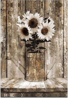 three sunflowers in a metal vase on an old wooden table with peeling paint