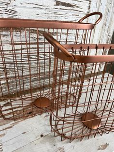 two metal baskets sitting on top of a wooden floor