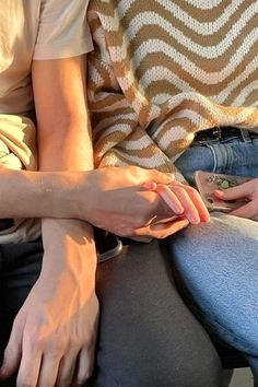 two people sitting next to each other with their hands on top of one another's legs