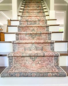 a carpeted stair case in the middle of a room with stairs and rugs