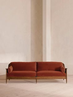 an orange couch sitting on top of a white floor next to a tall column in a room