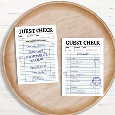 two guest check cards sitting on top of a wooden plate