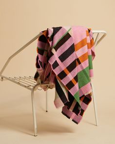 a pink and black blanket sitting on top of a white chair next to a wall