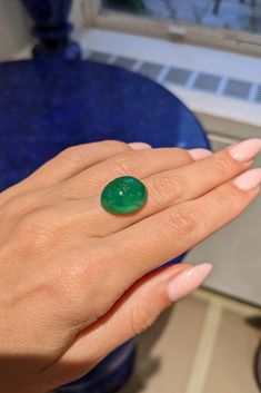 a woman's hand with a green ring on it