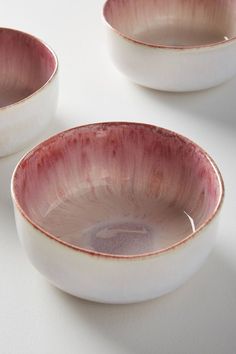 three white bowls sitting on top of a table next to each other with red rims