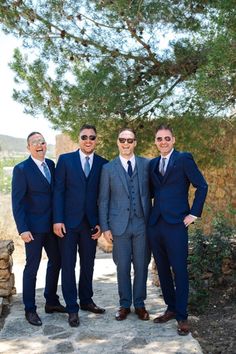 three men in suits and sunglasses are posing for a photo outside under the shade of a tree