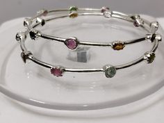 Beautiful Silver bangles exquisitely crafted by hand and designed with love. Genuine Handmade Tourmaline Bangle 925 Sterling Silver Flower Bangle-Multi Tourmaline Flower Bangles-Gemstone Bangle-multi Tourmaline Bangle > sold By 2 Piece PRODUCT DETAILS :- > Material - 925 Sterling Silver > Gemstone - Pink Tourmaline (100 %real ) > Gemstone shape - Oval > Gemstone Weight - 6.30 Ct > Gemstone Size- 4.6 mm > Setting - Pave setting > Gross Weight- 10.60 Grams Production Time: Each of our pieces are m Sterling Silver Bangle With Gemstone, Sterling Silver Bangle With Natural Stones, Multicolor Sterling Silver Bangle Bracelet, Adjustable Multicolor Gemstone Bangle, Multicolor Bangle With Natural Stones As A Gift, Round Stackable Tourmaline Jewelry, Stackable Round Tourmaline Jewelry, Tourmaline Birthstone Jewelry, Gift Multicolor Bangle With Natural Stones