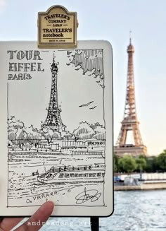 a hand holding up a travel book with the eiffel tower in the background