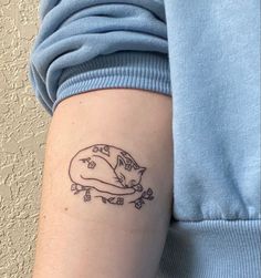 a woman's arm with a tattoo that has a cat sleeping on top of it