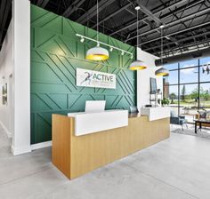 an office lobby with green walls and white counter tops, along with large windows that look out onto the outdoors