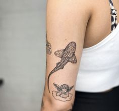 a woman's arm with tattoos on it and a shark in the sky above her