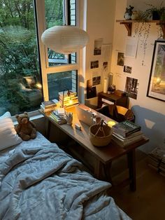 a bed sitting under a window next to a desk with a stuffed animal on it