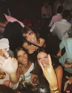 a group of women standing next to each other at a party with their hands in the air