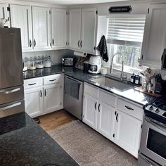 a kitchen with white cabinets and black counter tops