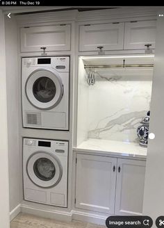 a washer and dryer in a small room with white cabinets on either side