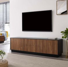 a flat screen tv mounted to the side of a wooden cabinet in a living room