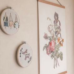 two embroidery hoops hanging on the wall next to each other with flowers in them