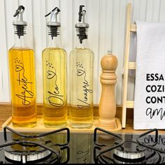 three bottles of liquid sitting on top of a burner next to a towel rack