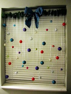 the window is decorated with balls hanging on a rod and ribbon tied at the top