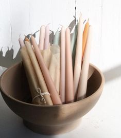 some candles are in a brown bowl on a white table and is tied with string