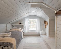 two beds in a small room with white walls and wood flooring on the ceiling