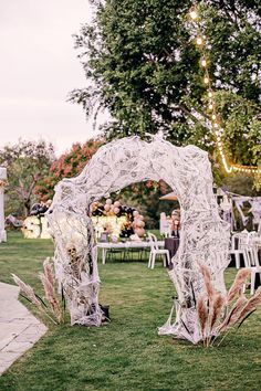 an outdoor wedding setup with chairs and tables in the grass, surrounded by string lights