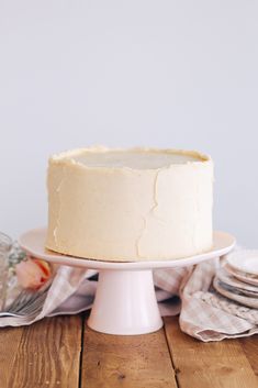 a frosted cake sitting on top of a wooden table next to plates and napkins