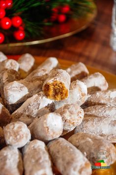 a plate full of snowball cookies on a table with christmas decorations in the background